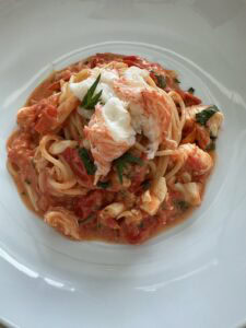 Creamy lobster pasta in a white plate.