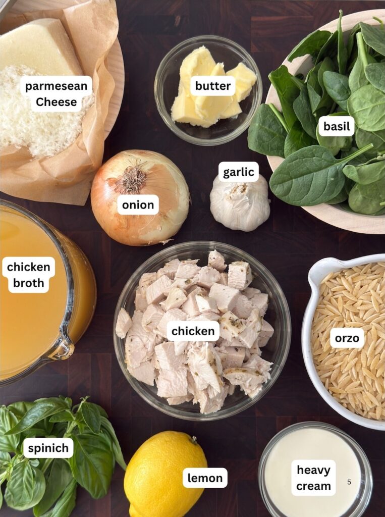 Ingredients for lemon chciken orzo in bowls on a dark wood cutting board