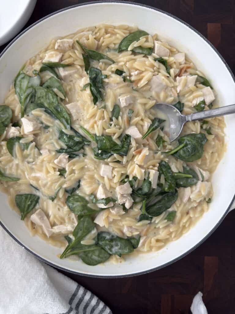 Overhead shot of the finished photo of the lemon chicken przo in a white bowl with serving spoon on a wooden cutting board.
