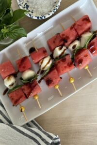 Watermelon and mozzarella skewers on a white serving platter