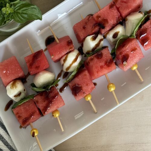 Watermelon and mozzarella skewers on a white serving platter