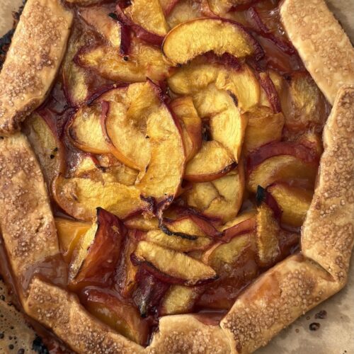 Golden brown baked peach crostata with flaky crust and caramelized peaches fresh from the oven.