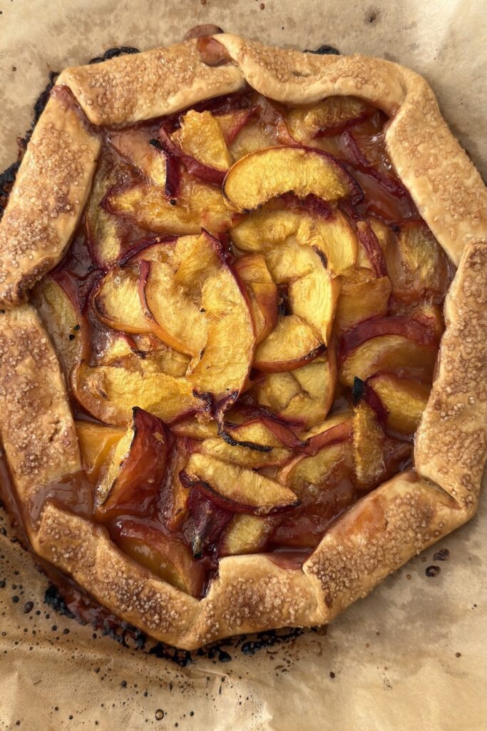 Golden brown baked peach crostata with flaky crust and caramelized peaches fresh from the oven.