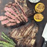 Grilled Italian steak sliced with lemon and herb sauce on cutting board