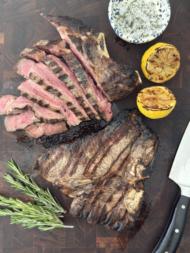 Grilled Italian steak sliced with lemon and herb sauce on cutting board