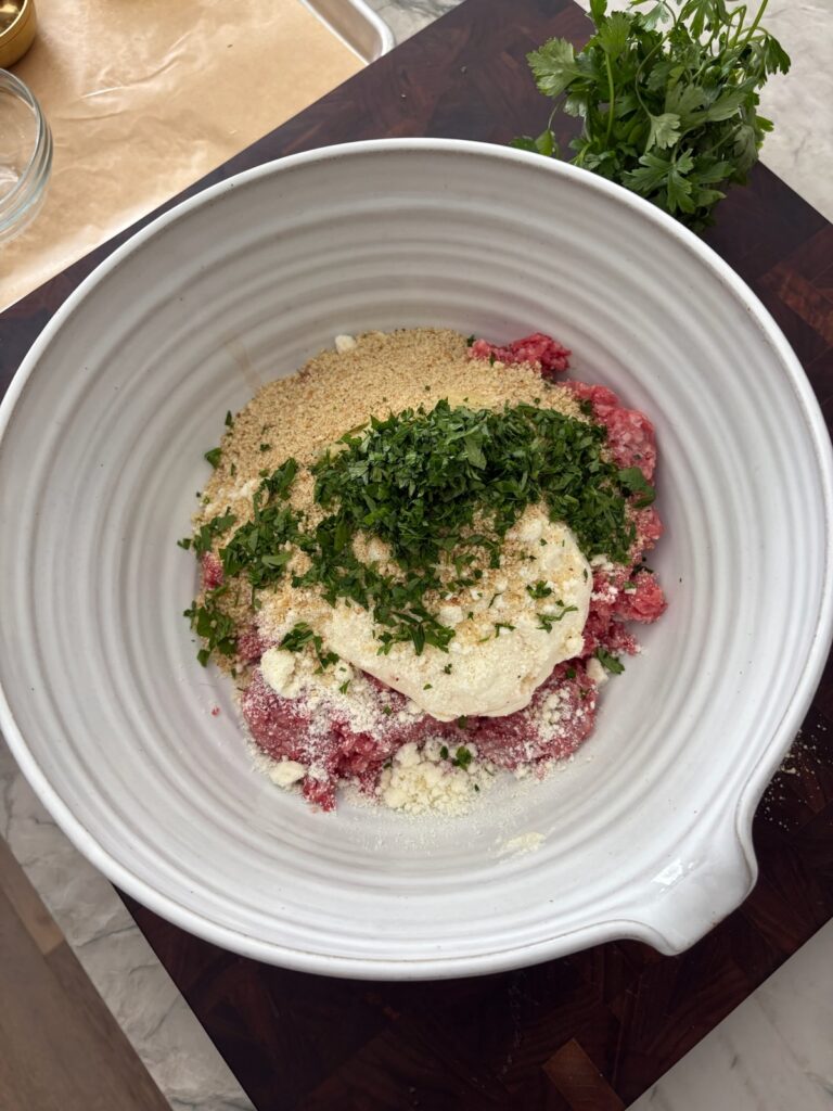 Mixing ricotta, parsley, garlic, and cheese for meatball flavor