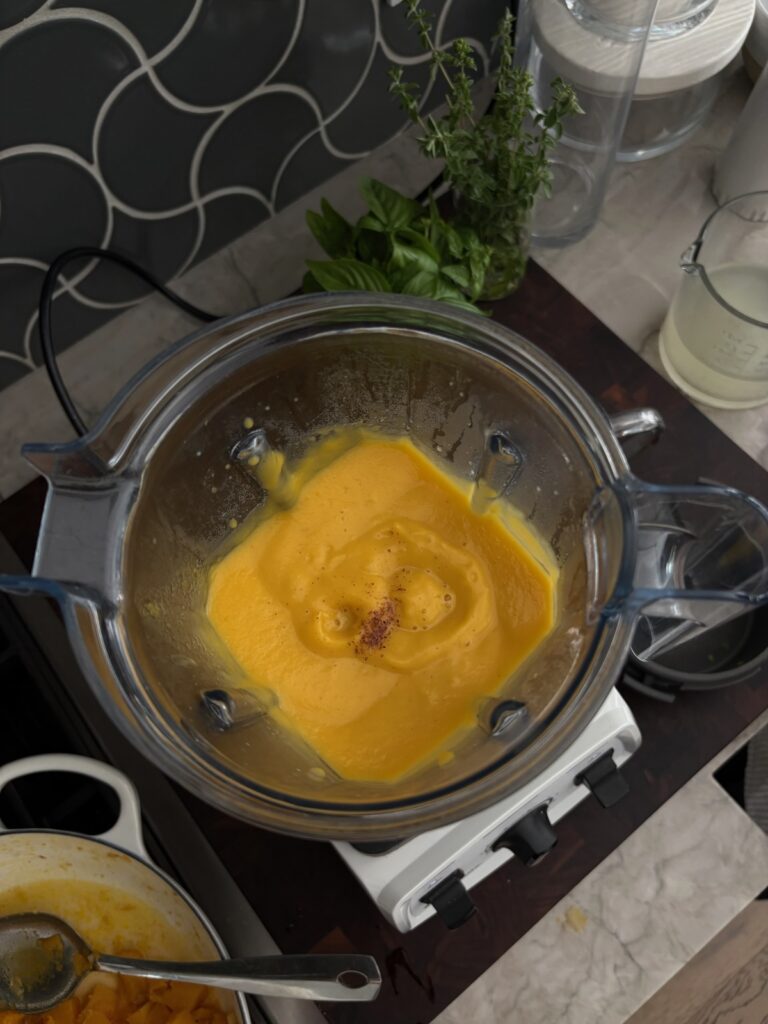 a photo of a blender with pureed butternut squash and nutmeg
