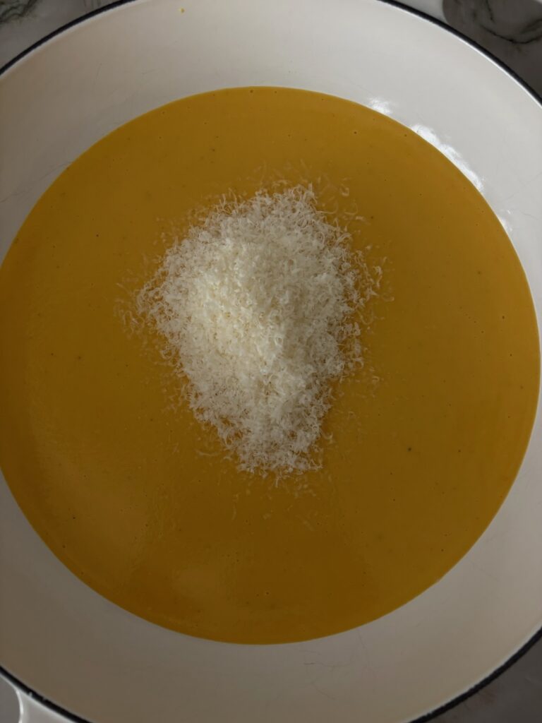 The pureed butternut squash in a large white serving bowl with fresh grated parmesan cheese.