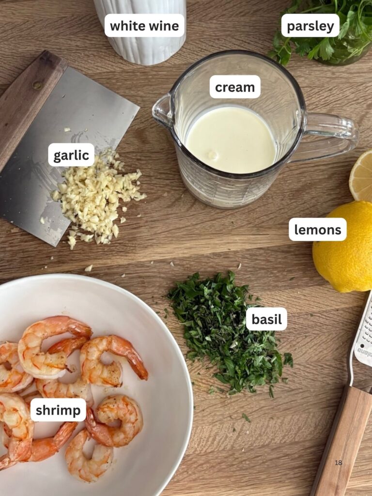 Ingredients for creamy garlic shrimp pasta, including cream, white wine, basil parsley, garlic, oregano, lemons, and cooked shrimp