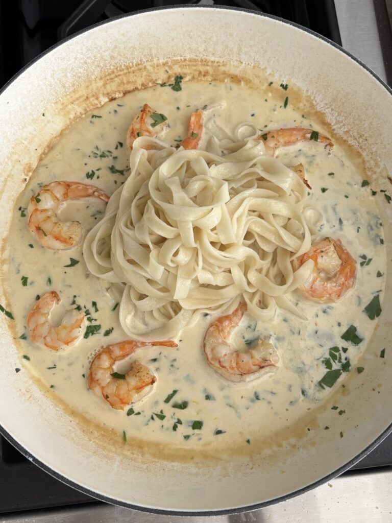Creamy garlic shrimp pasta with herbs in a white skillet