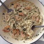 Creamy garlic shrimp pasta with herbs in a large white skillet, ready to serve