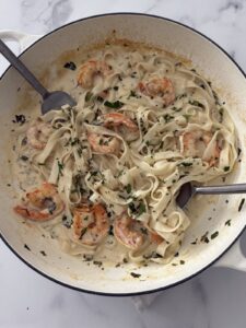 Creamy garlic shrimp pasta with herbs in a large white skillet, ready to serve