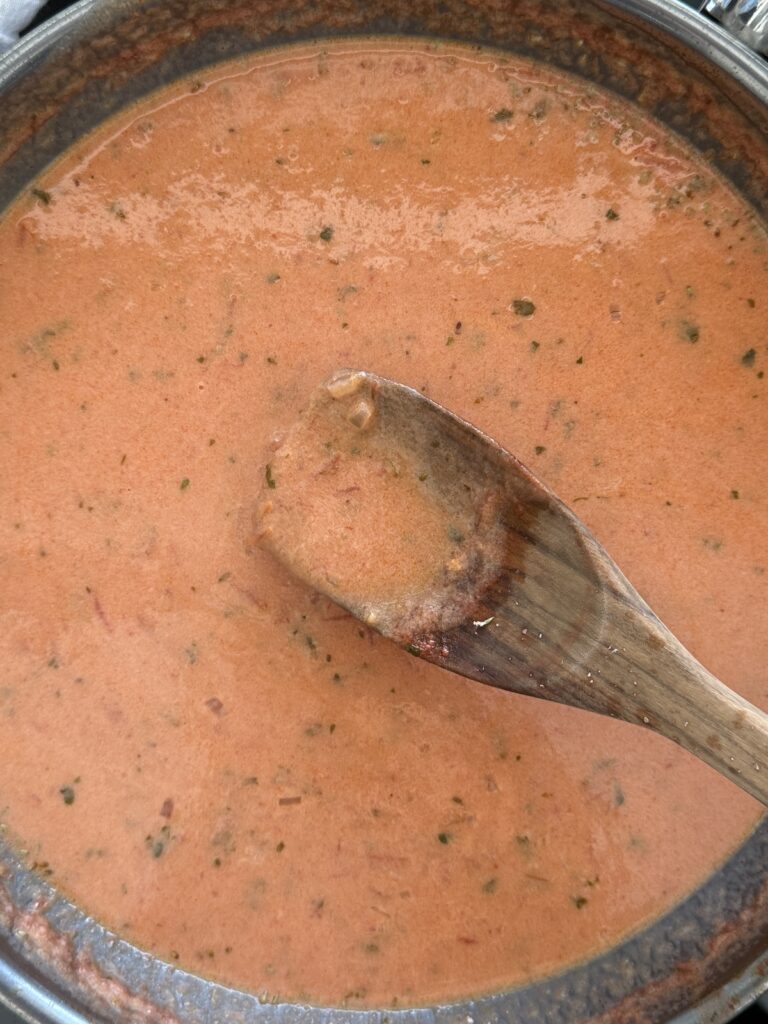 Tomato cream sauce simmering in a skillet for spicy shrimp pasta