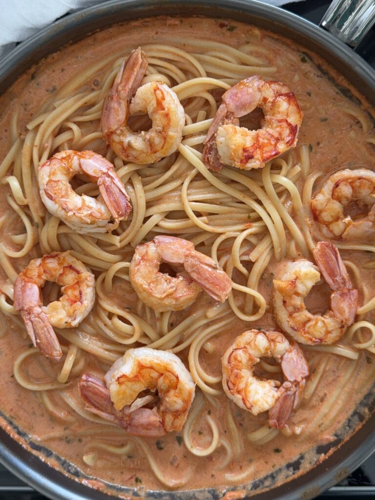 Overhead view of spicy shrimp pasta with creamy tomato sauce and basil