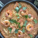 Bowl of spicy shrimp pasta topped with fresh basil ready to serve