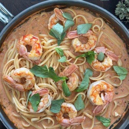 Bowl of spicy shrimp pasta topped with fresh basil ready to serve