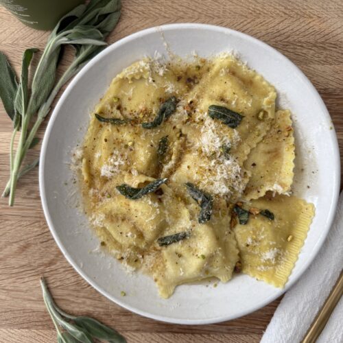 Butternut squash ravioli sprinkled with parmesan and pistachios, finished with crispy sage