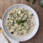 Homemade spinach and ricotta gnocchi served in a creamy sauce, garnished with fresh basil for an authentic Italian meal.