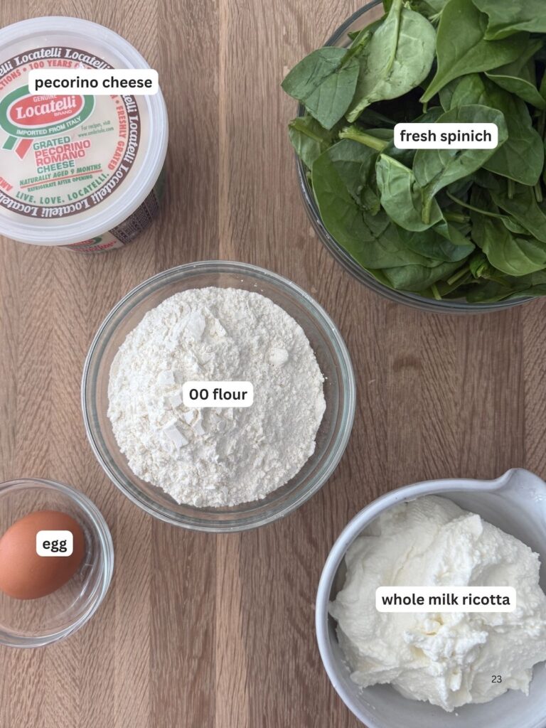 Ingredients for homemade spinach and ricotta gnocchi arranged on a wooden surface, including fresh spinach, 00 flour, whole milk ricotta, and Pecorino Romano cheese