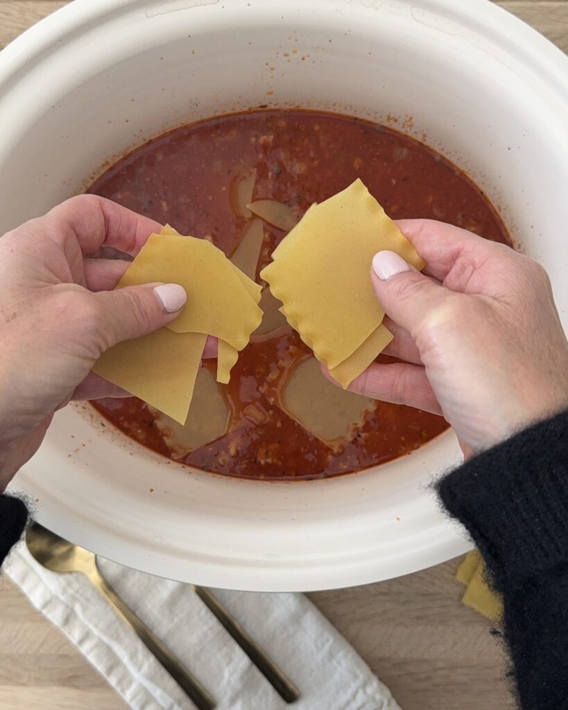 breaking up long lasagna noodles in the slow cooker to finish the lasagna soup recipe.