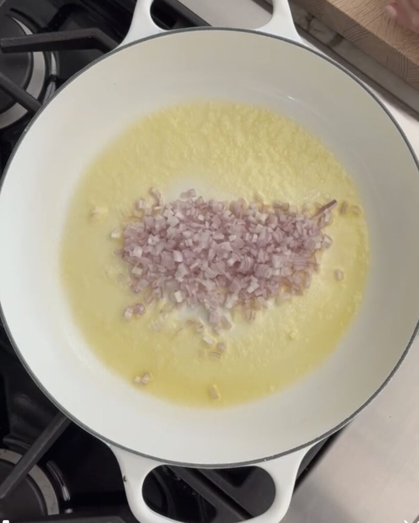 Chopped onion, butter, and oil sauteeing in a white pan for the pumpkin risotto base.