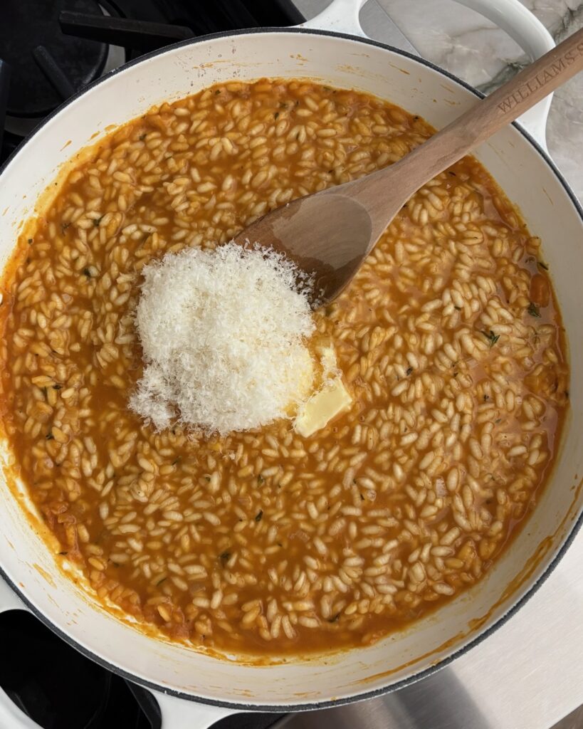 Adding butter and freshly grated Parmesan cheese to finish creamy pumpkin risotto.