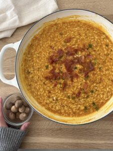 Creamy pumpkin risotto topped with crispy prosciutto and fresh thyme, ready to serve.