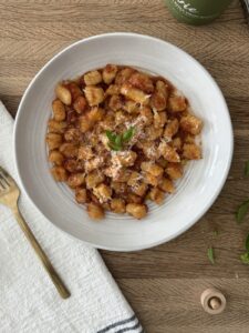 Bowl of homemade semolina pasta topped with tomato sauce, Parmesan cheese, and fresh basil.