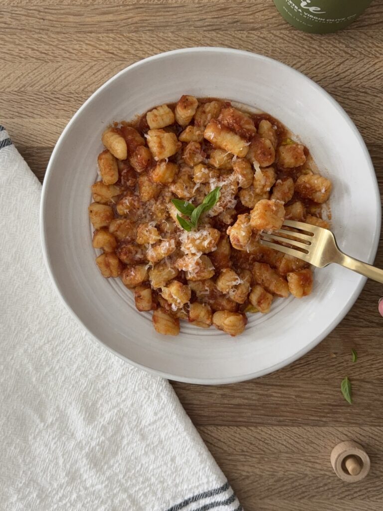 Bowl of homemade semolina pasta topped with tomato sauce, Parmesan cheese, and fresh basil.