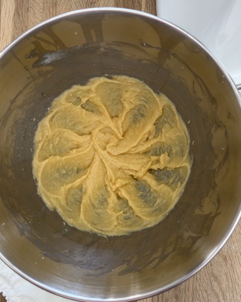 Creamed butter, sugar, and egg mixture in a mixing bowl for lemon ricotta cookie dough.