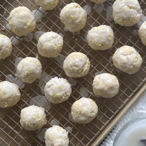 Lemon ricotta cookies freshly glazed with lemon icing, set on a wire rack to drip and dry.
