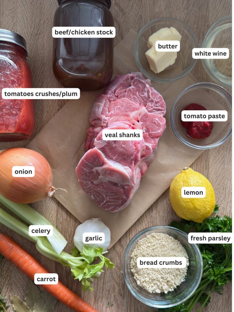 Ingredients for osso buco arranged on a board, including veal shanks, tomatoes, stock, white wine, butter, vegetables, and breadcrumbs for gremolata.