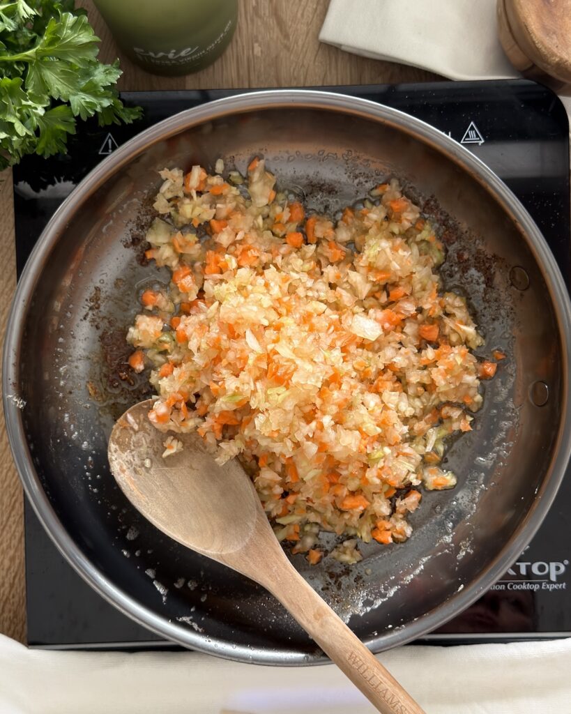 Onion, carrot, and celery soffritto sautéing in a skillet as the flavor base for slow cooker osso buco.