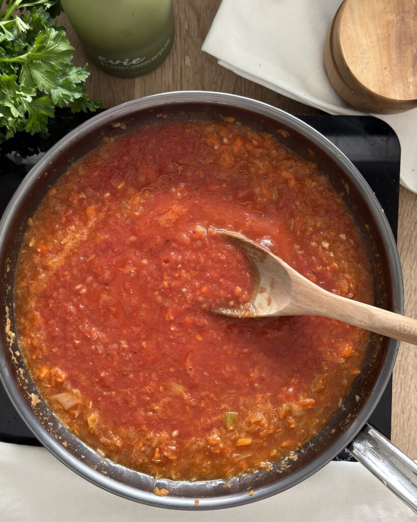 Tomato and vegetable braising sauce simmering in a skillet as the base for slow cooker osso buco.