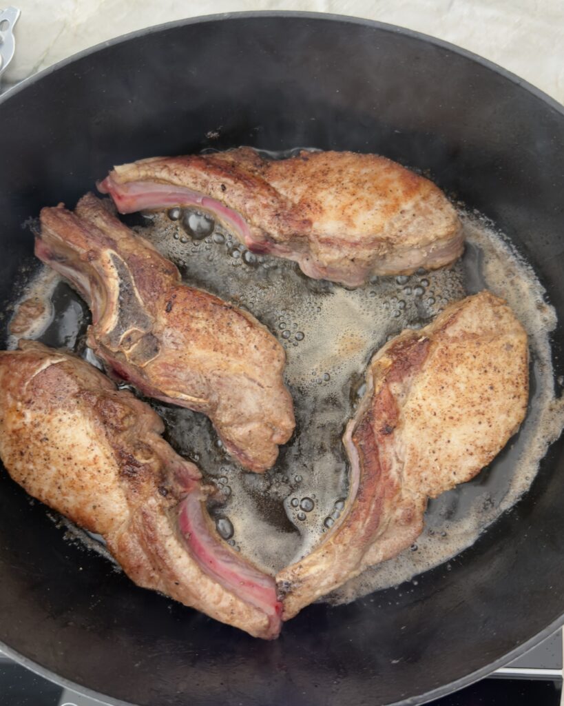 Bone-in beef short ribs and country-style pork ribs searing in a heavy pot for Italian Sunday sauce