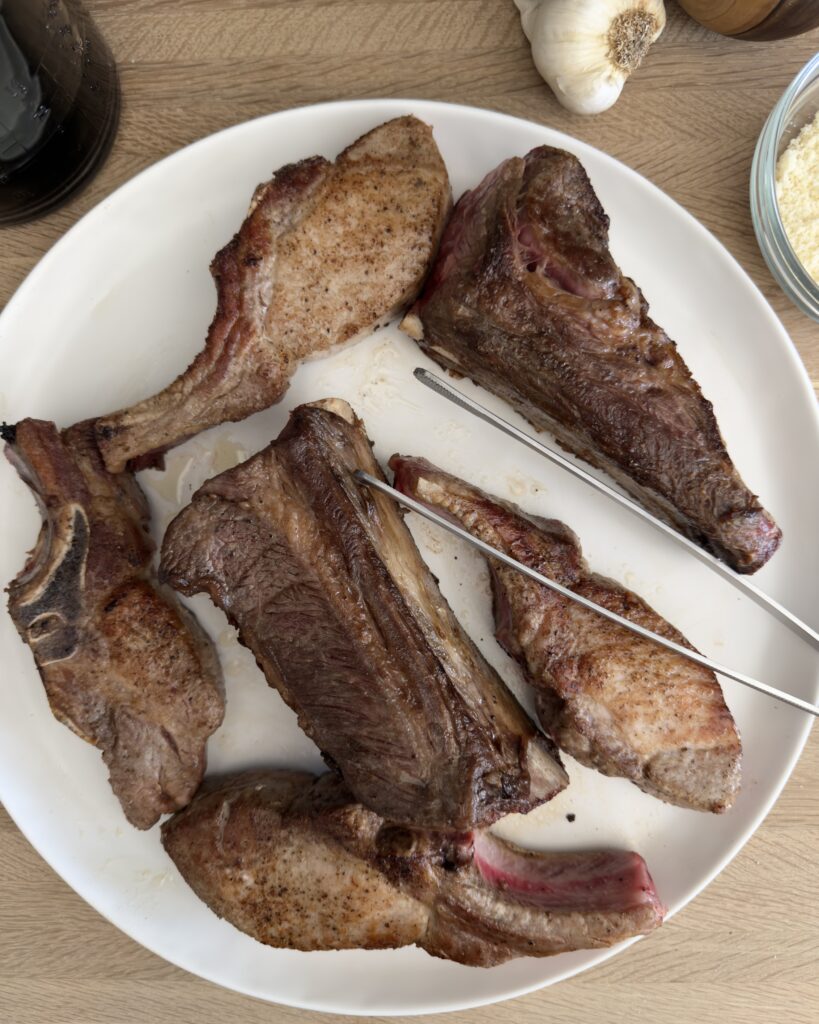 Browned bone-in beef short ribs and country-style pork ribs resting on a plate before simmering in Italian Sunday sauce