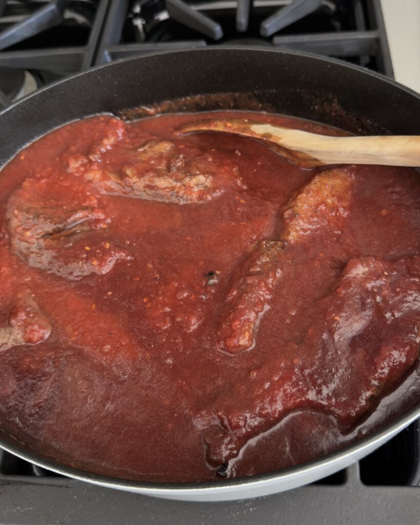Italian Sunday sauce simmering on the stove in the sauce with short ribs and country style ribs