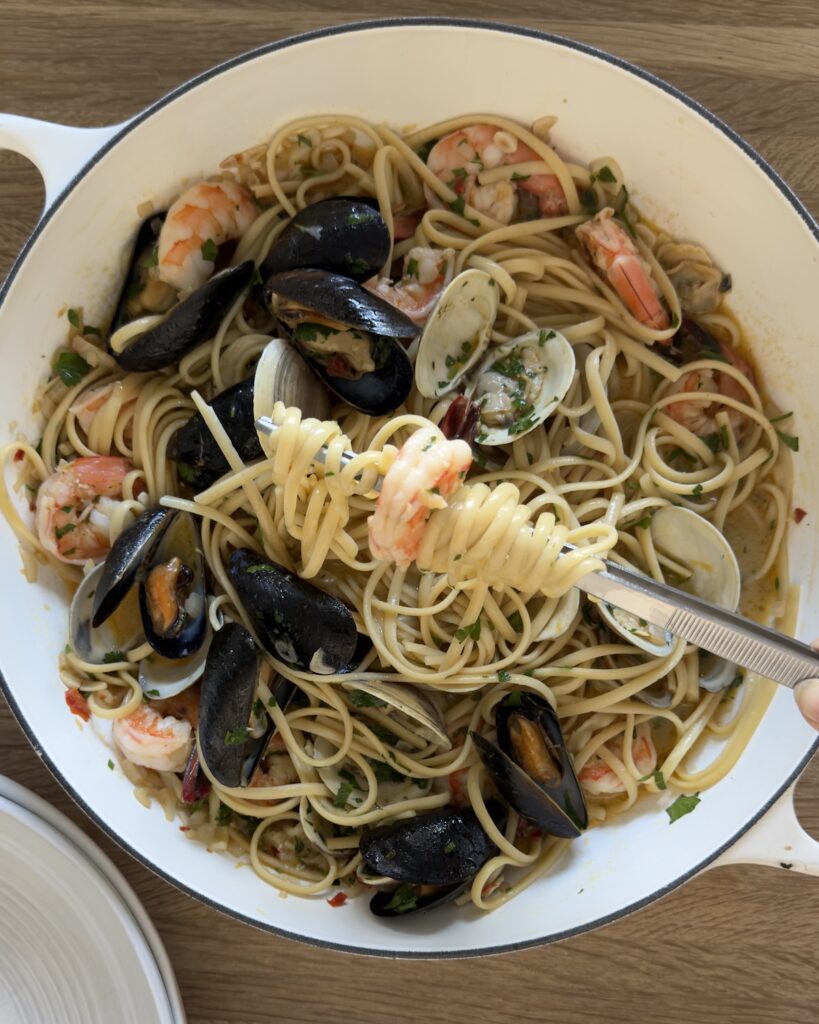 Fork twirling seafood linguine with clams, mussels, and shrimp in a white wine garlic sauce