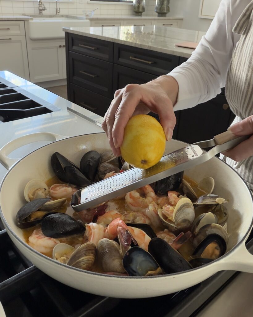 Fresh lemon zest added to clams, mussels, and shrimp simmering in a white wine garlic sauce