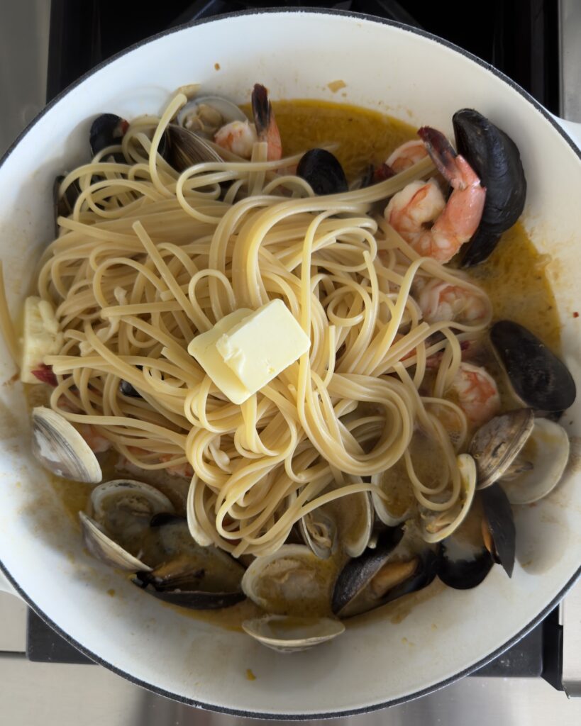 Pasta added to clams, mussels, and shrimp with butter melting into the sauce