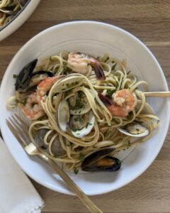 Seafood linguine with clams, mussels, and shrimp tossed in a white wine garlic sauce and served in a large white bowl