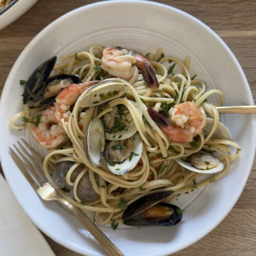 Seafood linguine with clams, mussels, and shrimp tossed in a white wine garlic sauce and served in a large white bowl