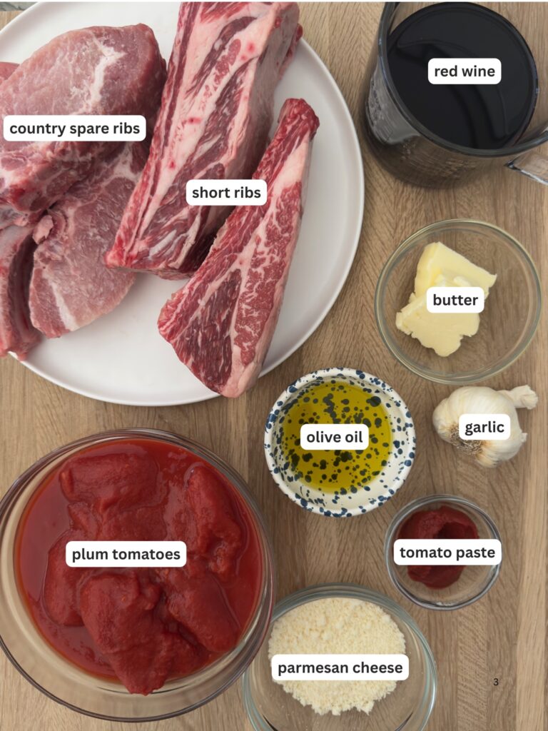 Ingredients for Italian Sunday sauce including beef short ribs, country-style pork ribs, tomatoes, red wine, garlic, olive oil, butter, and Parmesan cheese