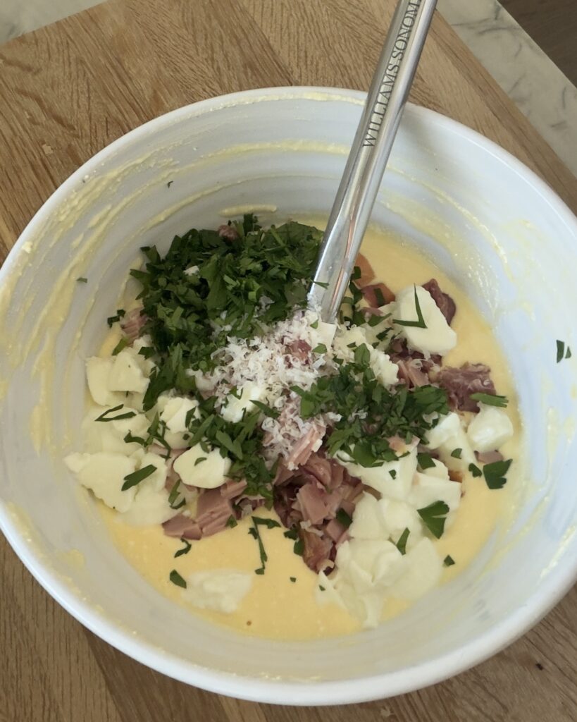 Italian Easter Pie filling with eggs, ricotta, prosciutto, mortadella, mozzarella, Parmesan cheese, and parsley in a mixing bowl