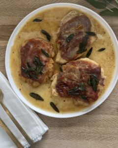 Chicken saltimbocca with prosciutto and fresh sage in a white wine butter sauce served in a shallow bowl
