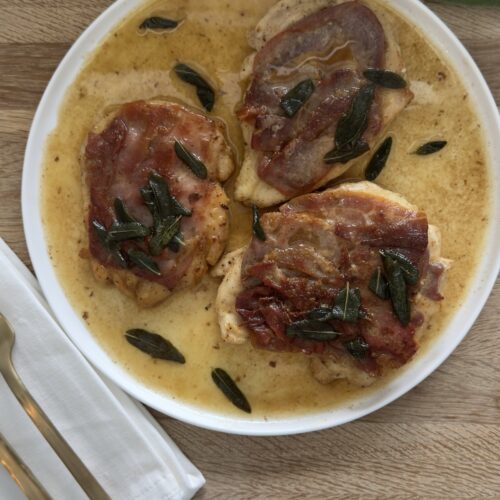 Chicken saltimbocca with prosciutto and fresh sage in a white wine butter sauce served in a shallow bowl