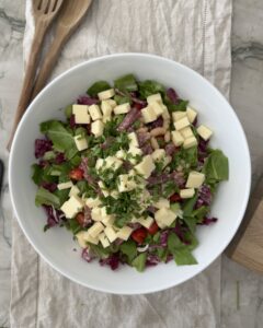 Italian chopped salad in a bowl with romaine lettuce, radicchio, provolone cheese, soppressata, cannellini beans, cherry tomatoes, olives, and fresh parsley before adding dressing.