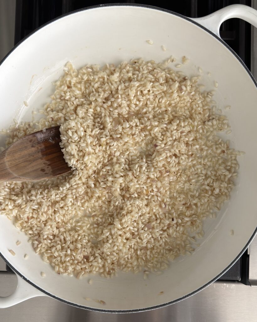 Arborio rice toasting in a pan with butter and olive oil for spring pea risotto.