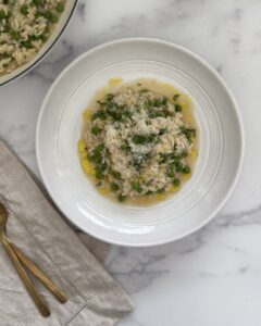 Spring pea risotto with Parmesan cheese, lemon zest, mint, and chives served in a bowl.