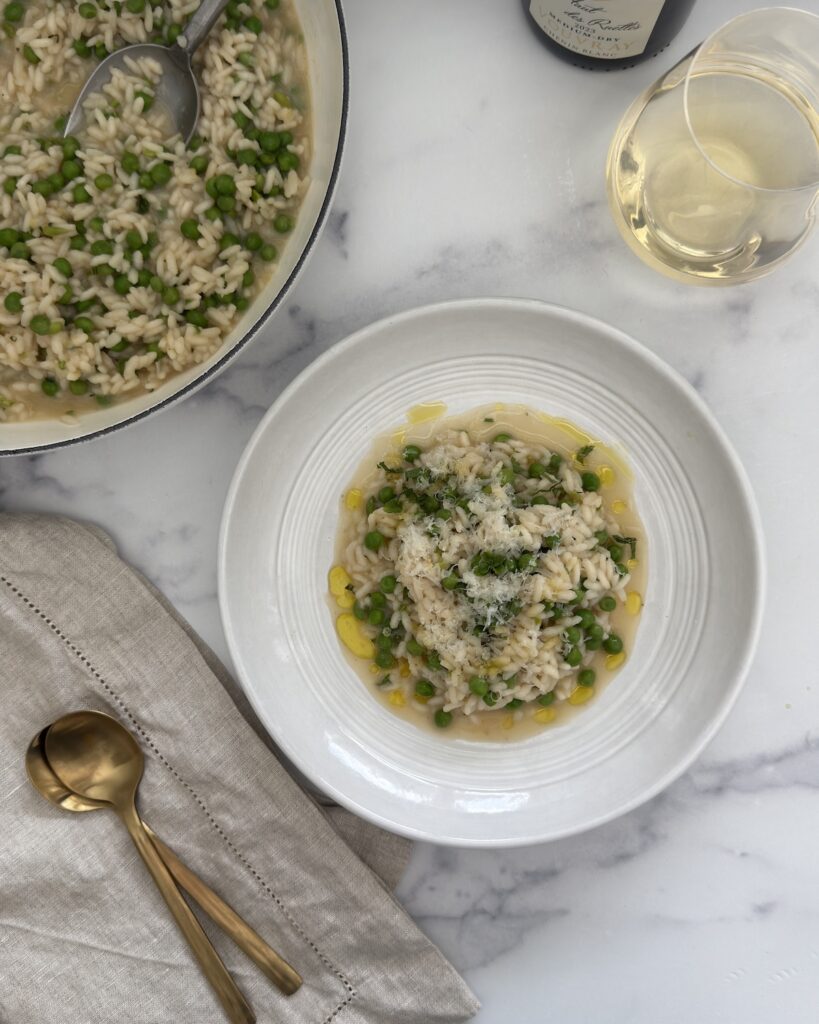 Spring pea risotto with Parmesan cheese, lemon zest, mint, and chives served in a bowl.